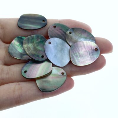 Eight iridescent mother-of-pearl shell pendants in hand, polished jewelry components.